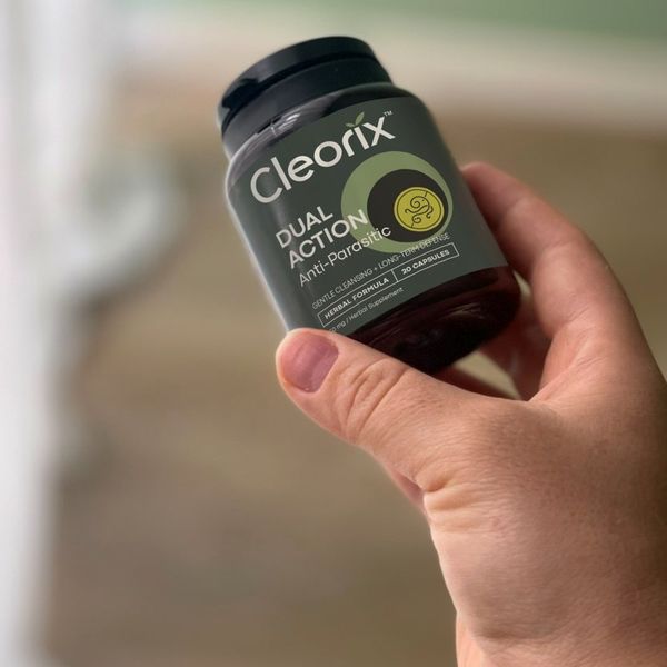 Sötétzöld Cleorix flakon 20 kapszulával, kézben tartva