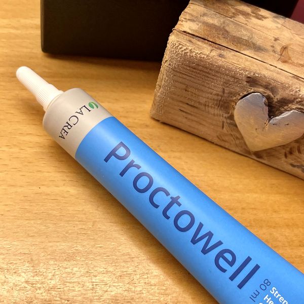Kék-fehér Proctowell tubus hosszú applikátorral, fa asztalon